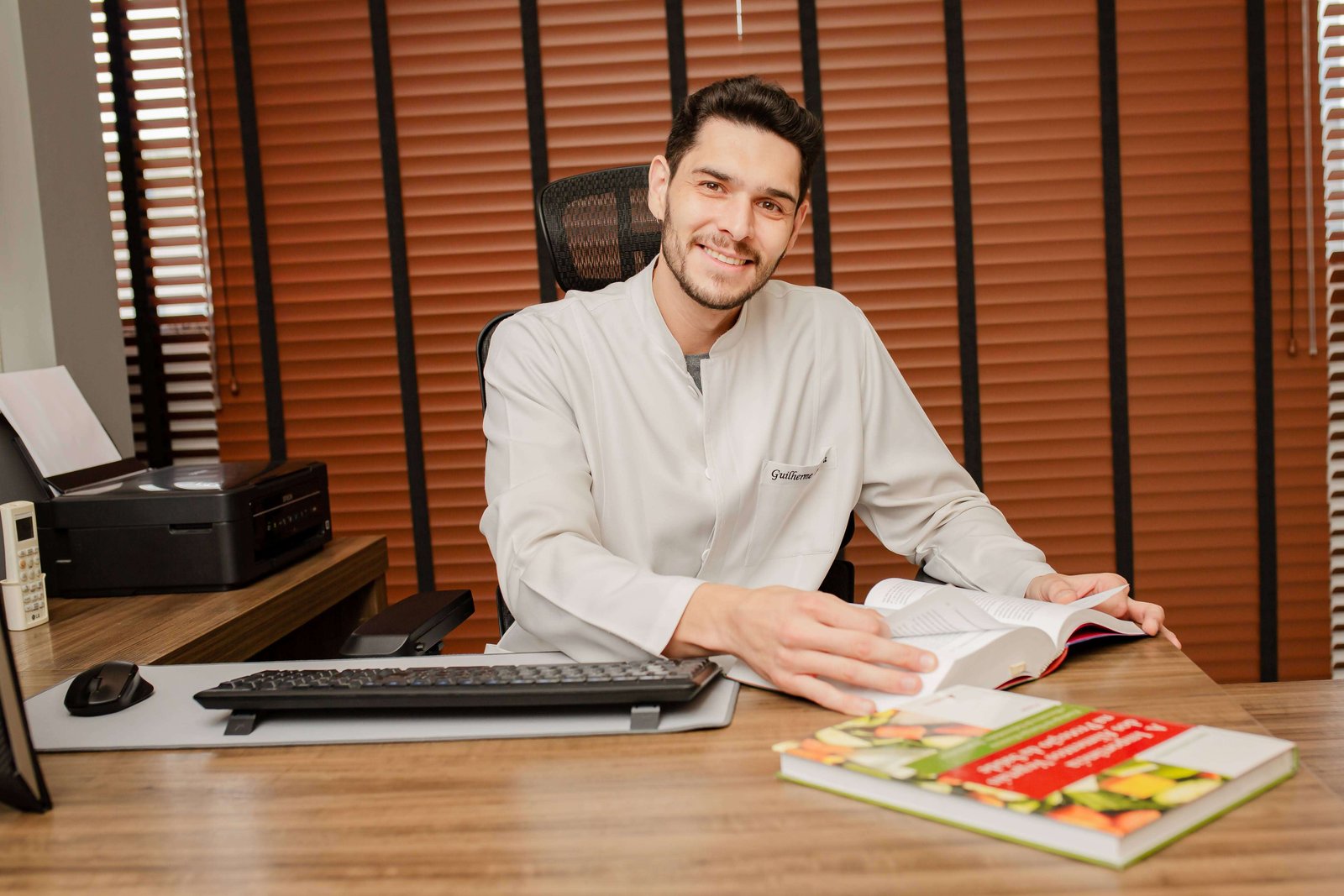 Guilherme Oliveira, nutricionista, sorrindo em seu consultório em Itaúna